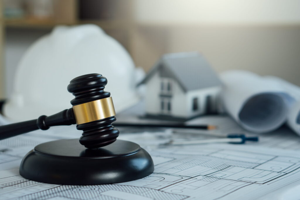 A judge's gavel resting on architectural blueprints beside a small house model and rolled construction plans, symbolizing Ontario zoning laws, municipal by-law enforcement, and the legal approval process required for land development and rezoning applications.