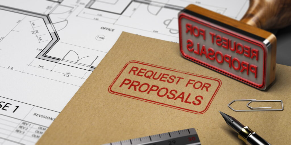 A brown envelope stamped with "Request for Proposals" resting on architectural drawings, with a rubber stamp, fountain pen, and ruler, representing the formal building permit application submission process in Ontario.