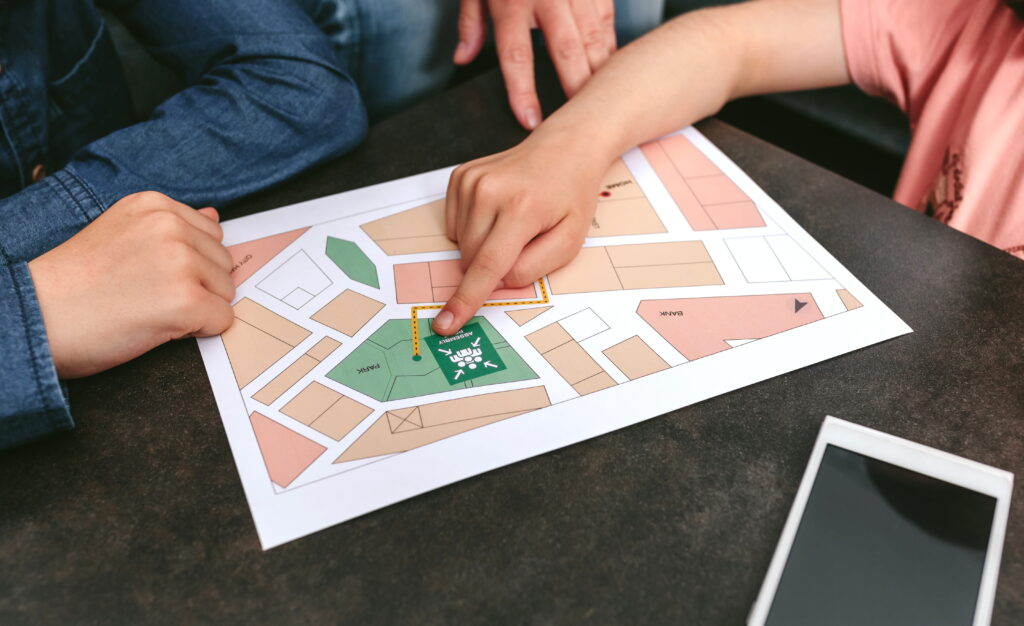 Two people pointing at a printed zoning map showing residential, commercial, park, and open space zones, representing the process of accessing and understanding Ontario zoning information before a land development project.