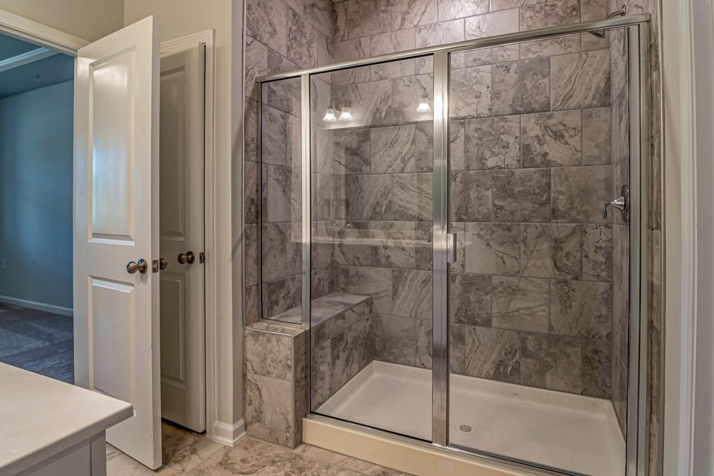 Marble-tiled walk-in shower with glass doors